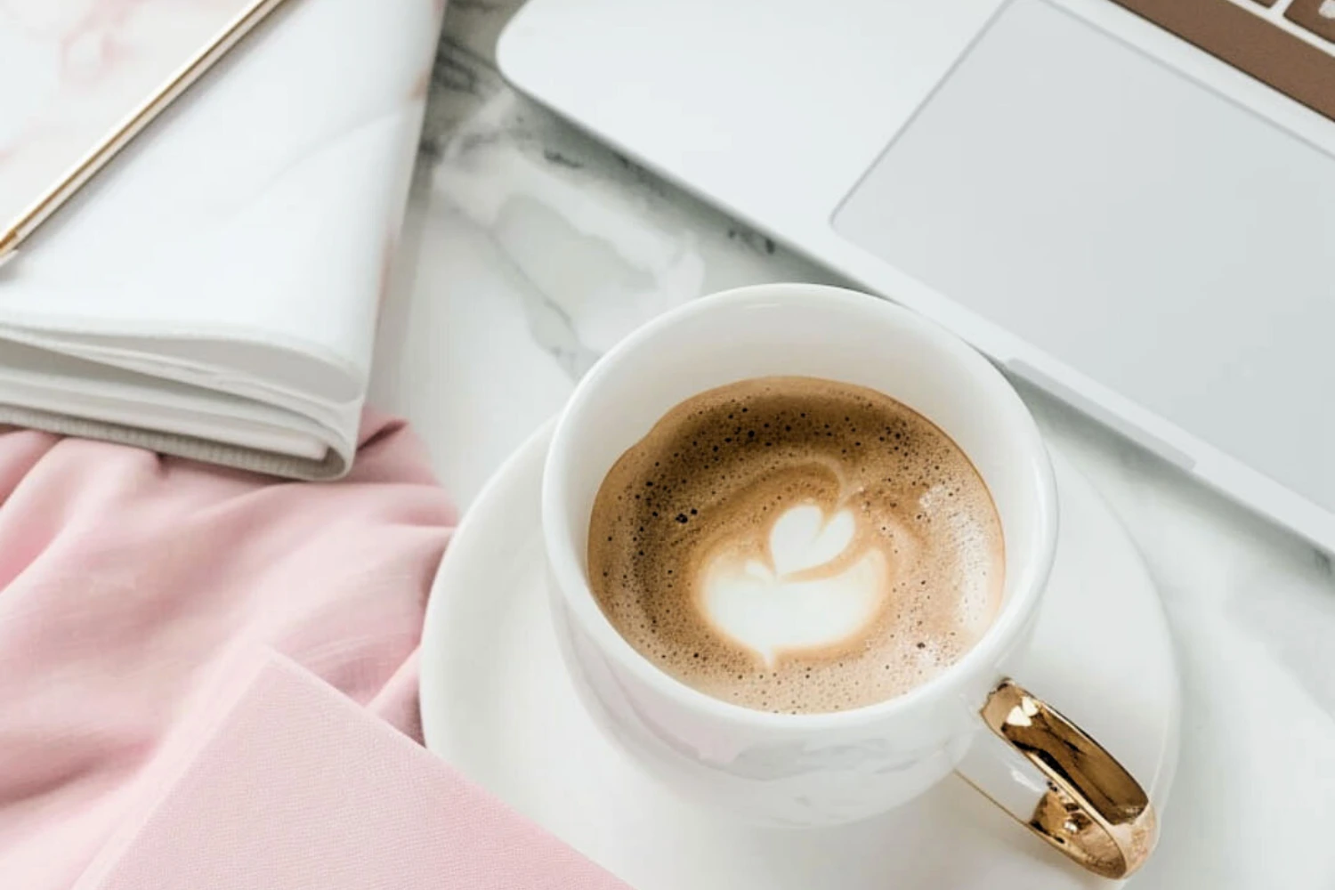 A coffee cup next to a laptop